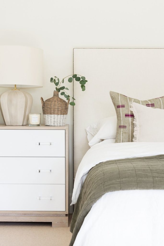 bedroom with white and wood nightstand and upholstered headboard.
