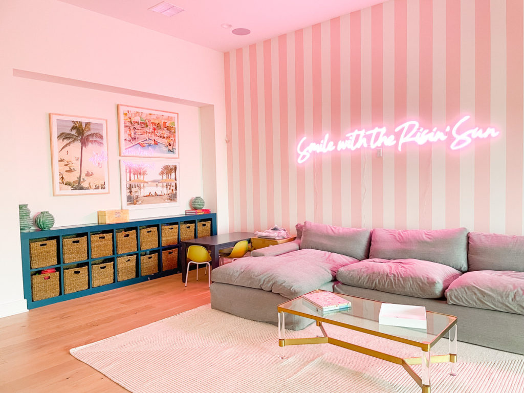 Pink and white striped wall and neon sign in playroom.