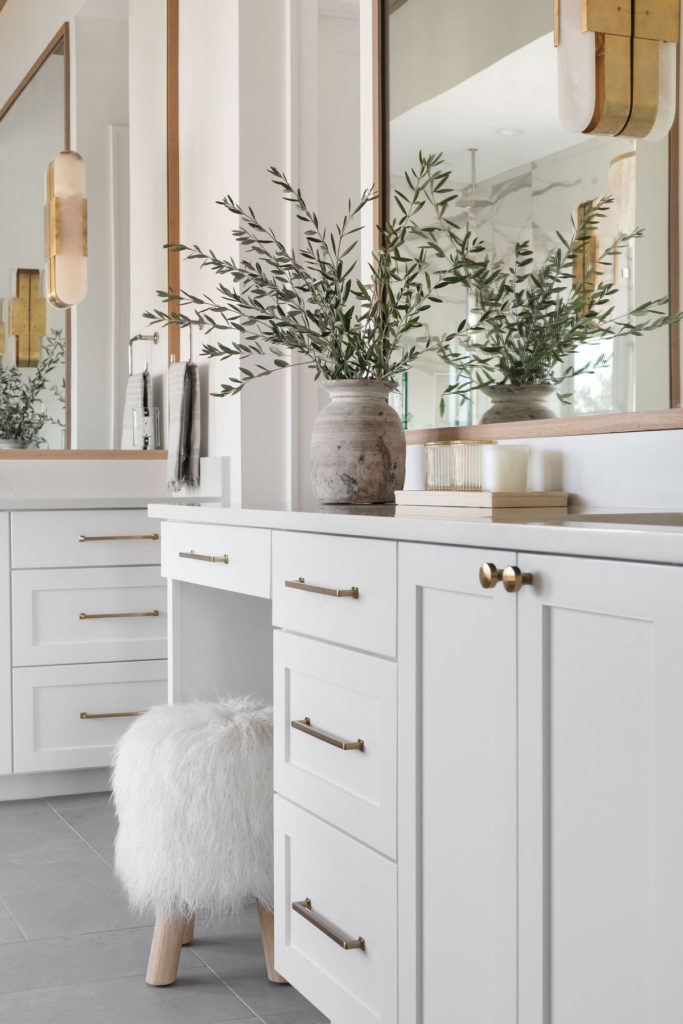 Gold cabinet hardware on white vanity with gray tile floor.